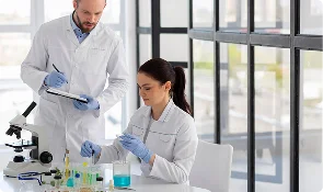 Two researchers in lab coats reviewing peptide research samples on a laboratory bench