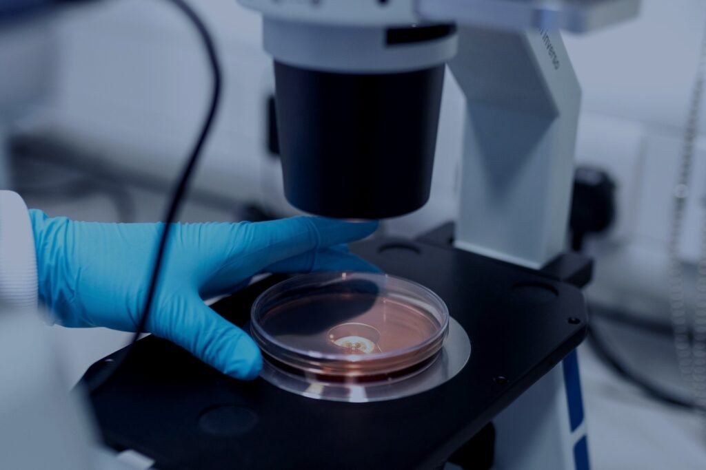 Gloved hand placing a petri dish under a microscope – PerformanceLabs UK